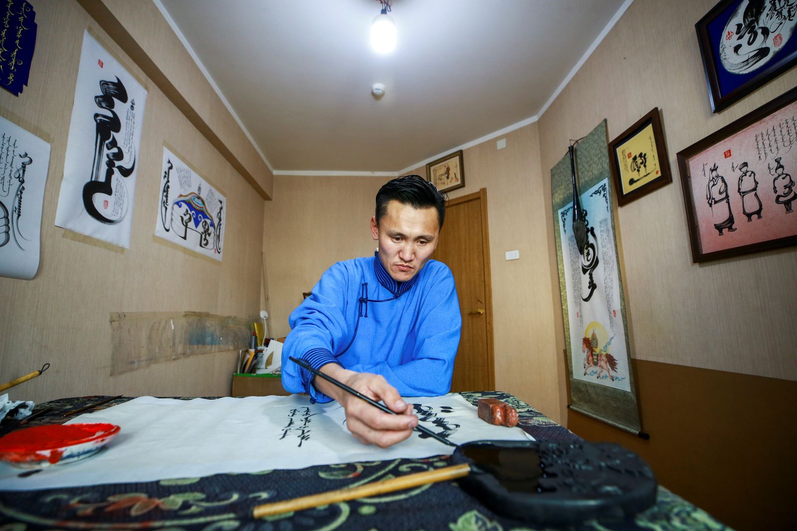 الخطاط جانزوريغ جولغو، الذي يكسب المال عن طريق بيع أعماله الفنية للخط بشكل أساسي، يكتب نصوصاً منغولية في منزله في أولان باتور، عاصمة منغوليا - AFP