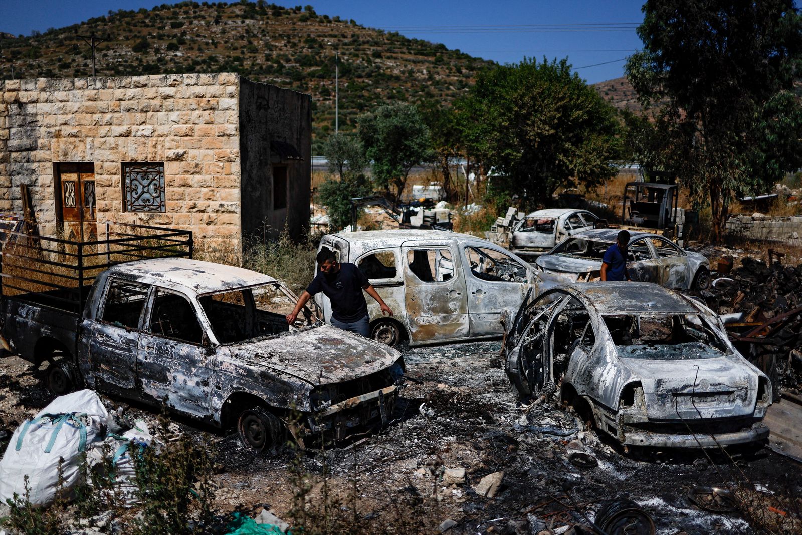 فلسطينيون يتفقدون سيارات محترقة بعد هجوم للمستوطنين الإسرائيليين بالقرب من رام الله في الضفة الغربية المحتلة. 21 يونيو 2023