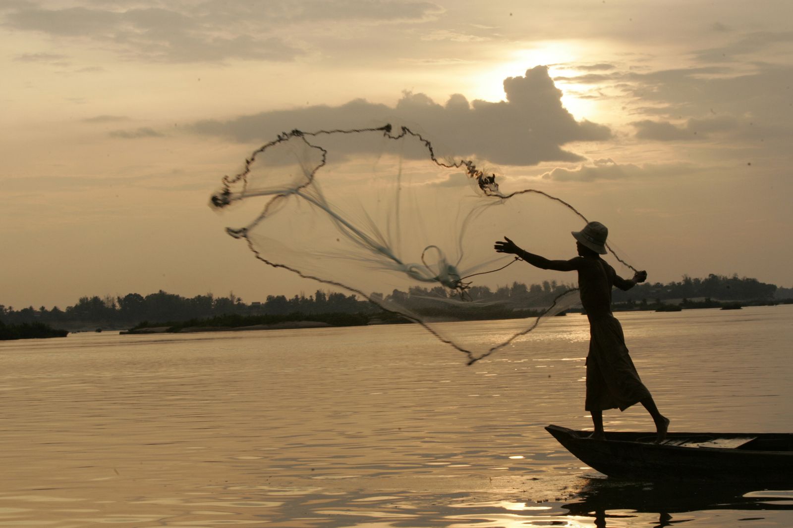 صياد يلقي بشبكة على نهر ميكونج موطن دلافين إيراوادي، حيث سنت الحكومة قراراً بمضاعفة عقوبة الصيد بالشباك، في قرية كامبي في مقاطعة كراتيي شمال شرق كمبوديا - 24 مارس 2007 - Reuters