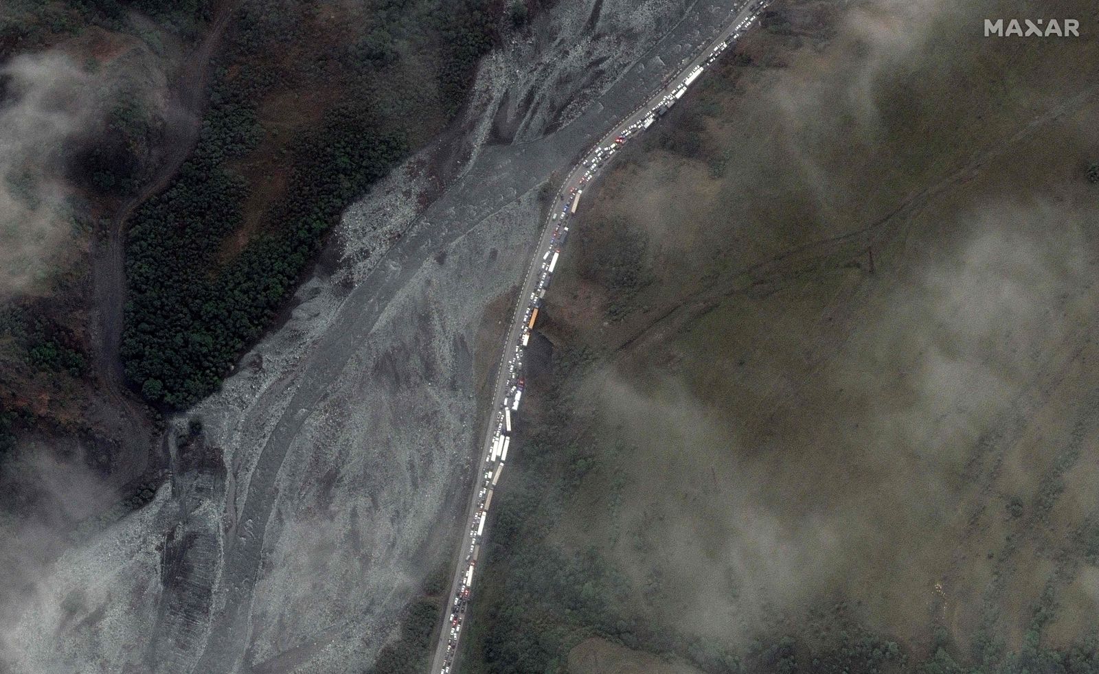 This handout satellite image released by Maxar Technologies on September 26, 2022 and taken on September 25, 2022 shows trucks and cars waiting in traffic jam near the Russian border with Georgia. - According to Kazakhstan's interior ministry, around 98,000 Russians entered the country since the mobilisation was announced on September 21, while just over 64,000 left, the RIA Novosti news agency reported. Meanwhile, long queues to leave the country formed at Russia's border with the Caucasus nation of Georgia, with officials admitting an " border="