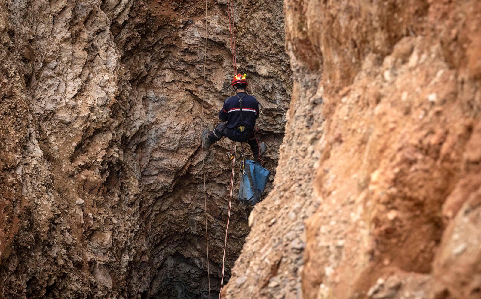 A Moroccan emergency climber work to rescue five-year-old boy Rayan from a well shaft he fell into on February 1, in the remote village of Ighrane in the rural northern province of Chefchaouen on February 4, 2022. - Moroccan rescuers were in the nerve-wracking final stages of a marathon effort to rescue Rayan, a five-year-old boy trapped down a well for a fourth night. (Photo by Fadel SENNA / AFP) - AFP