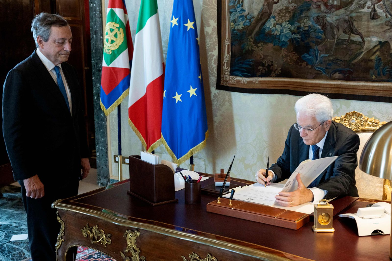 TOPSHOT - This handout photo taken and released on July 21, 2022, by the press office of the presidential Quirinale Palace shows Italian President Sergio Mattarella (R) signing the decrete to dissolve the Parliament in front of Italy resigning Prime Minister Mario Draghi (L). - Draghi resigned on July 21, after the country's fractious parties torpedoed his national unity government, kicking off a snap election campaign which could bring the far-right to power. (Photo by Handout / Quirinale Press Office / AFP) / RESTRICTED TO EDITORIAL USE - MANDATORY CREDIT 