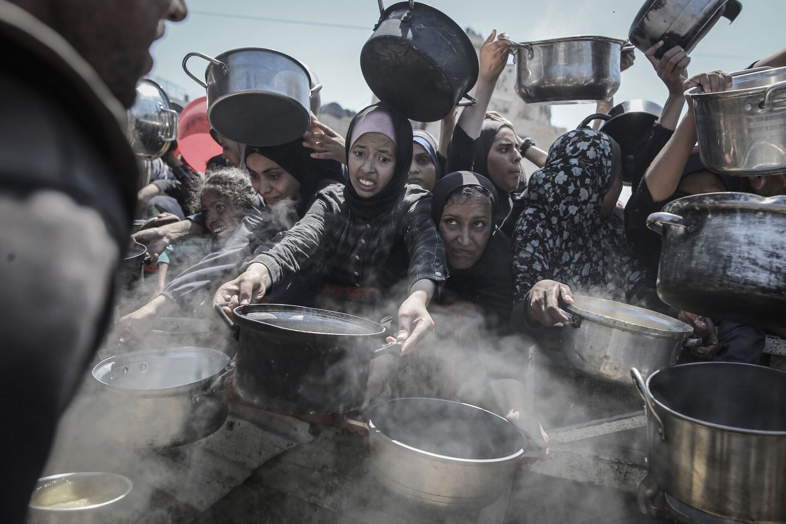 Palestinians hold out pots and pans to collect free food from a charity kitchen in Gaza City, Gaza, on Monday, Aug. 4, 2025. The US may weigh in 'massively' on efforts to alleviate humanitarian conditions in Gaza and is discussing post-war scenarios for the Palestinian enclave, Israeli Foreign Minister Gideon Sa'ar said. Photographer: Ahmad Salem/Bloomberg