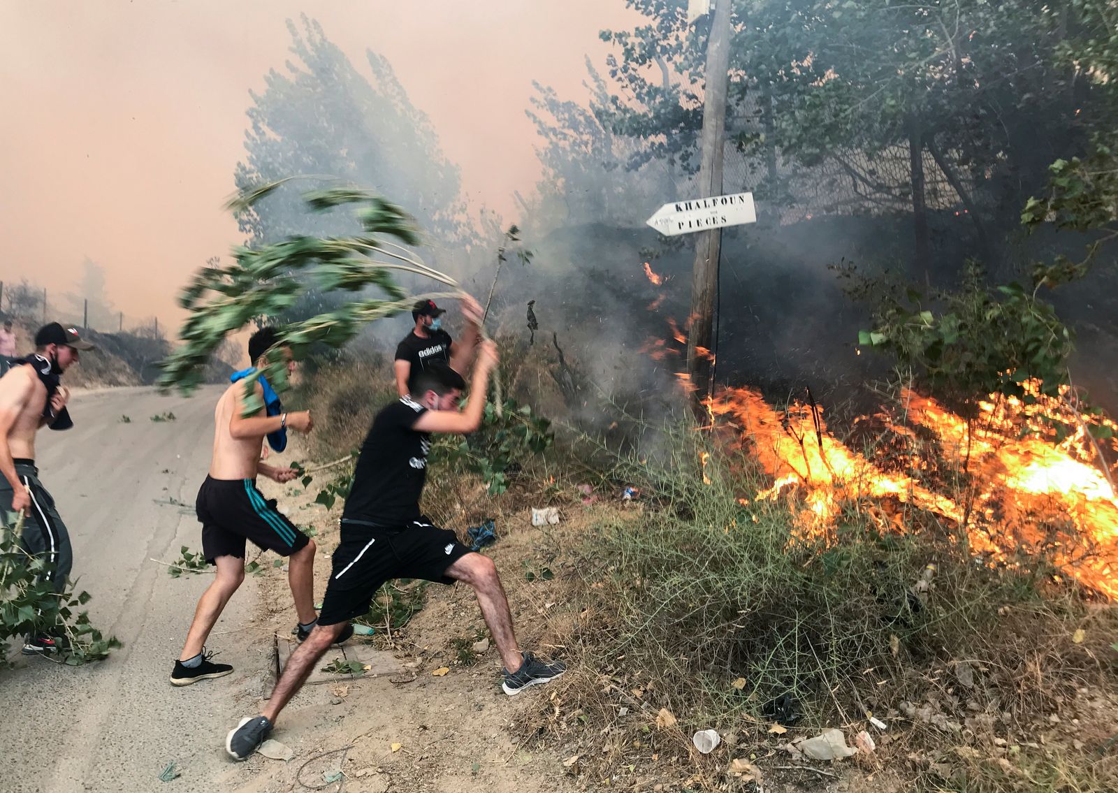 شبان يحاولون إطفاء الحرائق بواسطة أغصان الأشجار. - REUTERS - REUTERS