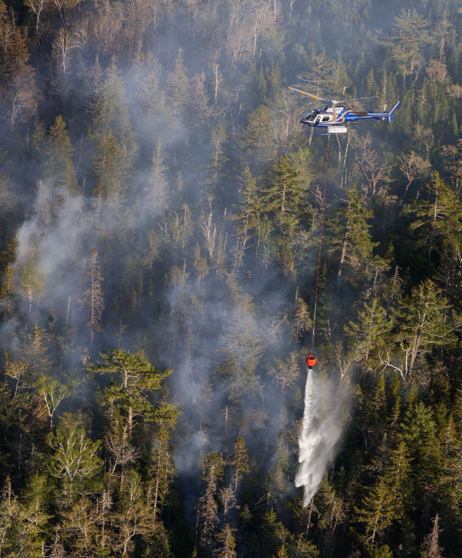 In this May 29, 2023, aerial image courtesy of the Nova Scotia Government in Canada, a helicopter drops water on the Tantallon wildfire, west of Halifax. More than 16,000 people were forced to evacuate their homes in Canada's eastern province of Nova Scotia, officials said Monday, as one of hundreds of wildfires raging across the country threatened the city of Halifax. (Photo by Handout / Nova Scotia Government / AFP) / RESTRICTED TO EDITORIAL USE - MANDATORY CREDIT 