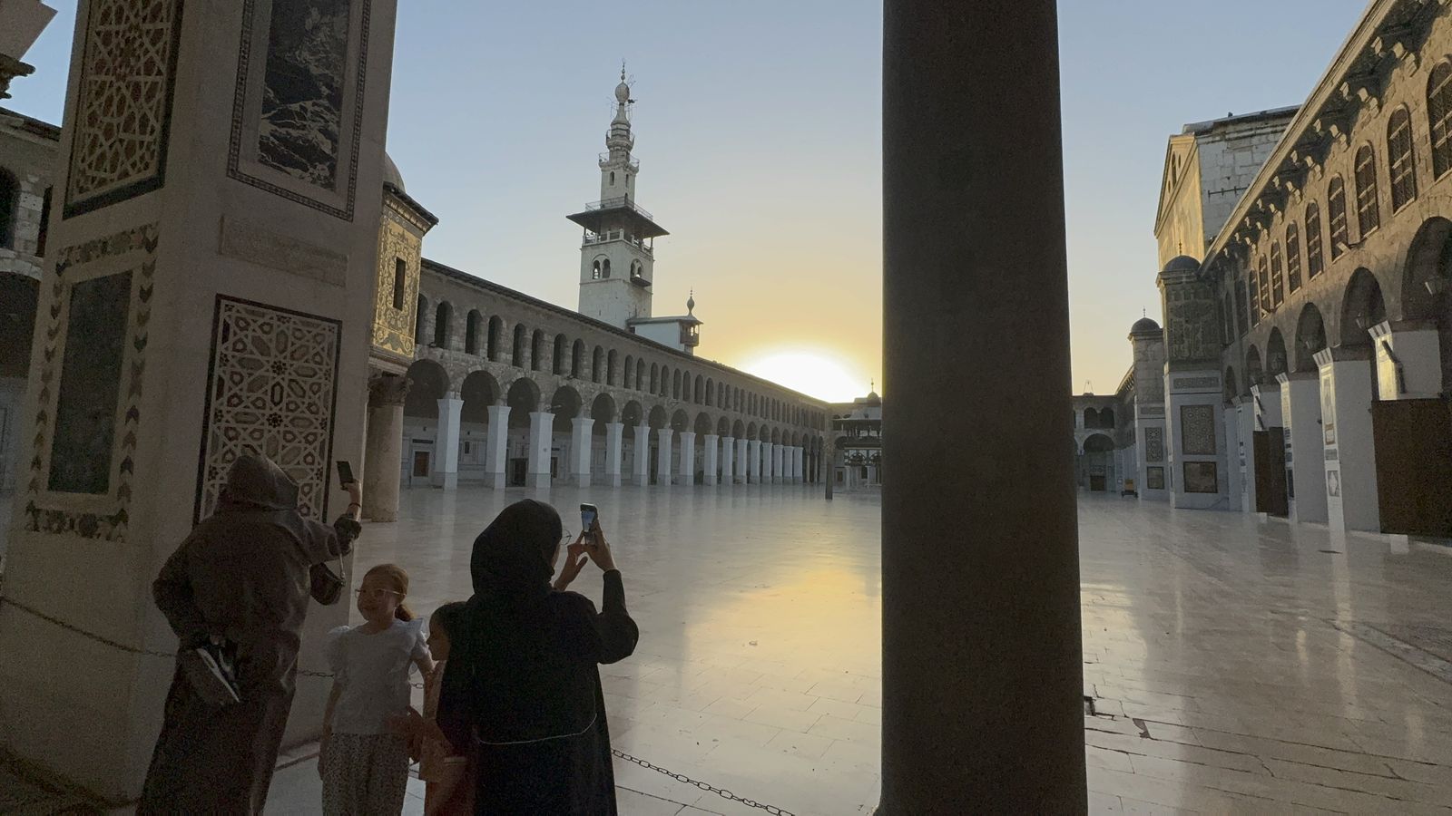 سوريتان تلتقطان صورا بهواتف محمولة لساحة المسجد الأموي الكبير في العاصمة دمشق قبل أداء صلاة عيد الأضحى (16 يونيو حزيران 2024)