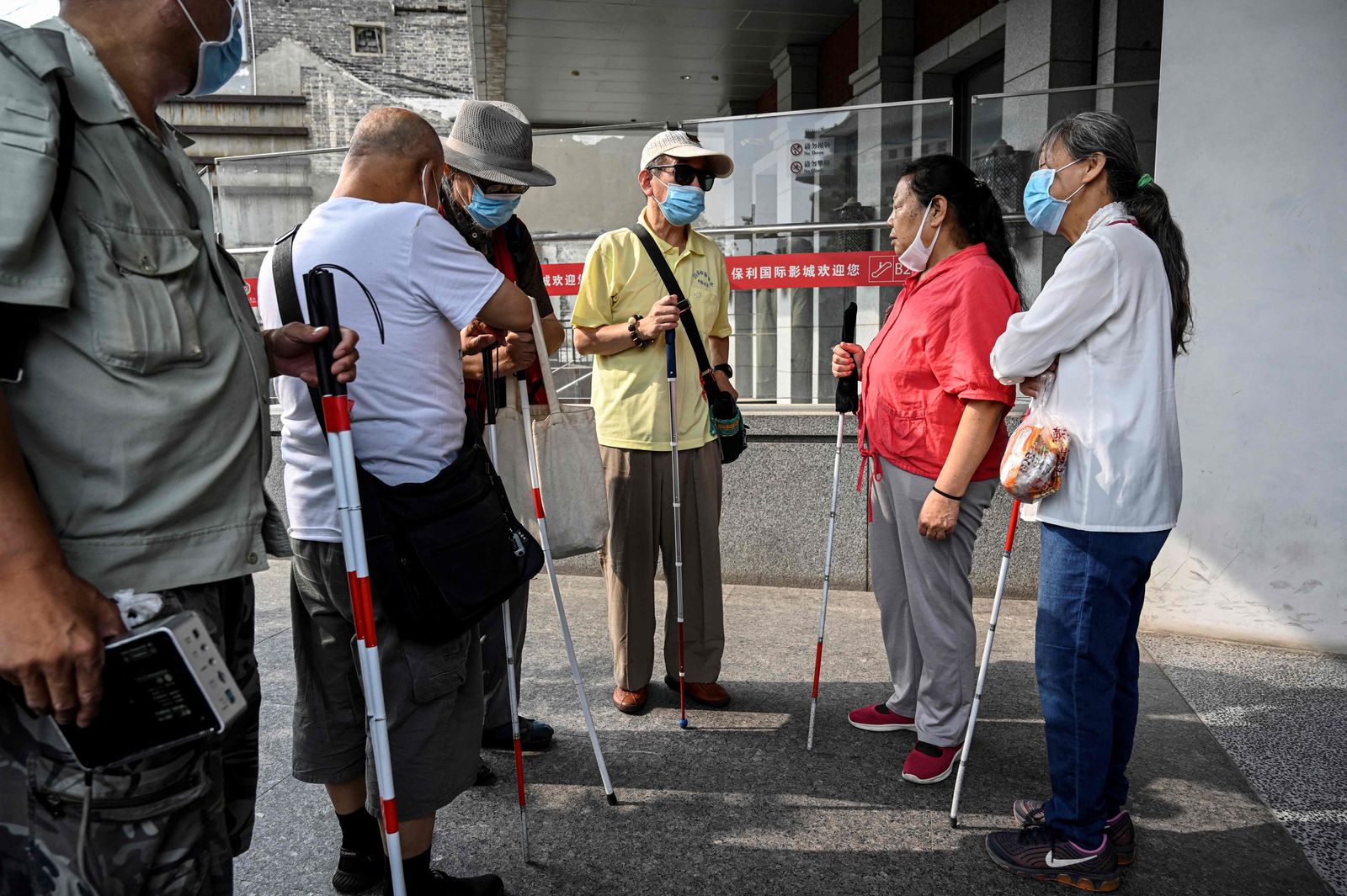 This photo taken on August 7, 2021 shows visually impaired people gathering at the entrance of a cinema in Beijing. - Dozens of blind moviegoers come to the Saturday screenings organised by Xin Mu Theater, a small group of volunteers who were the first to introduce films to blind audiences in China. (Photo by Jade GAO / AFP) / To go with AFP story China-social-disabled-film, FEATURE by Poornima WEERASEKARA and Danni ZHU - AFP