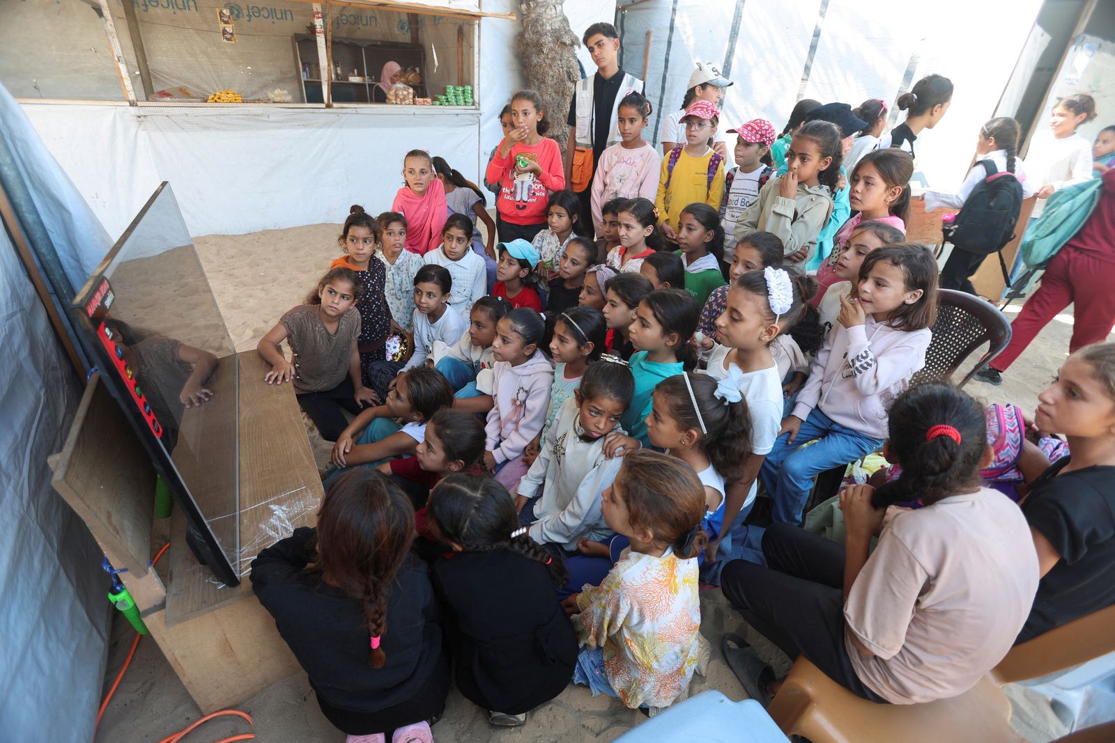 Palestinian children watch a cartoon movie during an activity held by the Palestinian Red Crescent Society, aimed at easing the psychological stress caused by the war, in Khan Younis in the southern Gaza Strip, October 28, 2025. REUTERS/Ramadan Abed REFILE - QUALITY REPEAT