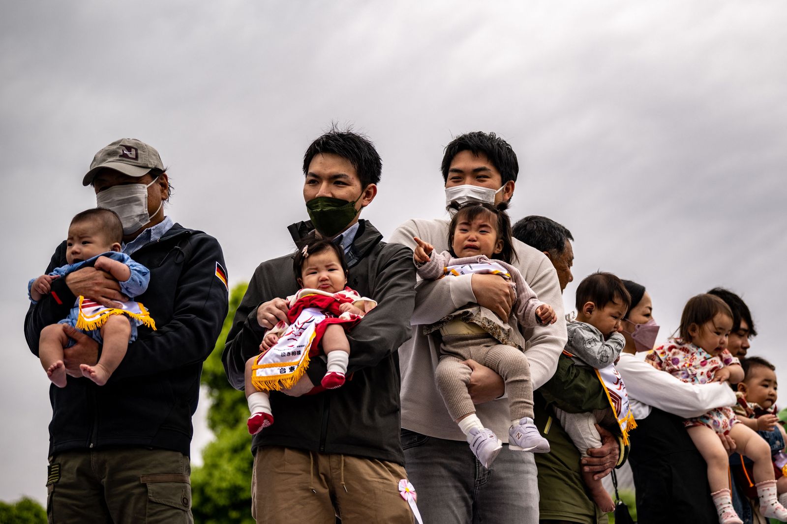 Children held by their parents stand before their 