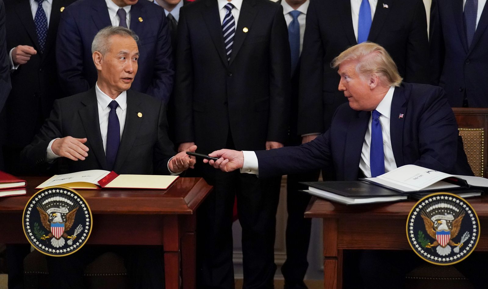 نائب رئيس مجلس الدولة الصيني ليو هي يستلم قلمًا من الرئيس الأمريكي السابق دونالد ترمب بعد توقيع 