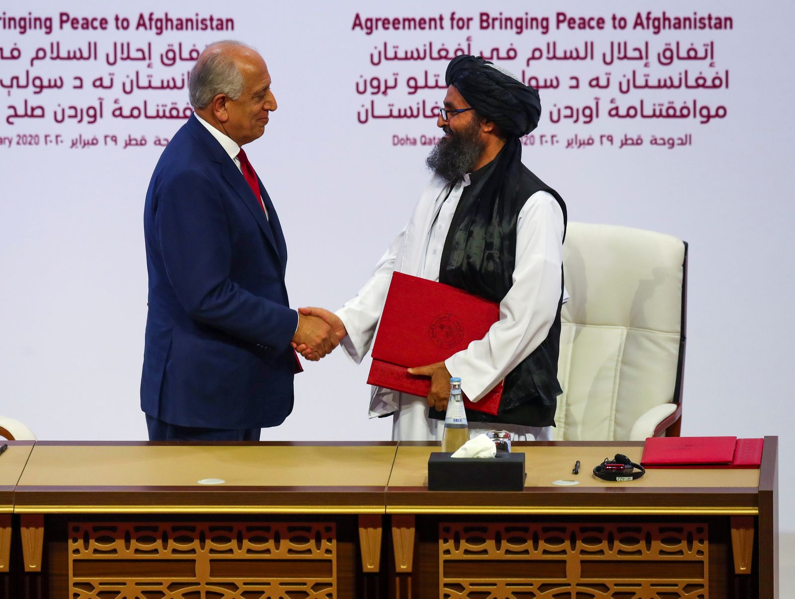 المبعوث الأميركي الخاص للمصالحة الأفغانية زلماي خليل زاد ونائب رئيس طالبان ملا عبدالغني برادار خلال توقيع الاتفاق بين الجانبين في الدوحة 29 فبراير 2020 - REUTERS