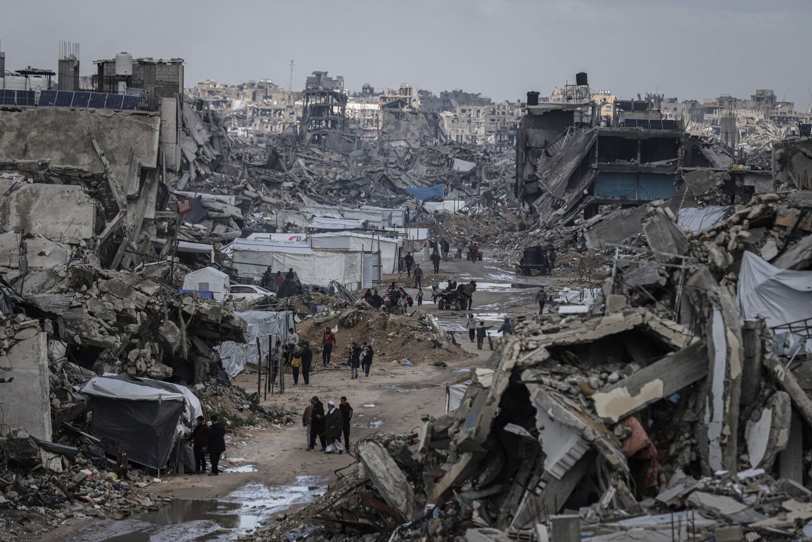 فلسطينيون يمشون بين أنقاض مبان مدمرة في مخيم جباليا للاجئين بشمال قطاع غزة جراء الهجمات الإسرائيلية. 13 فبراير 2025