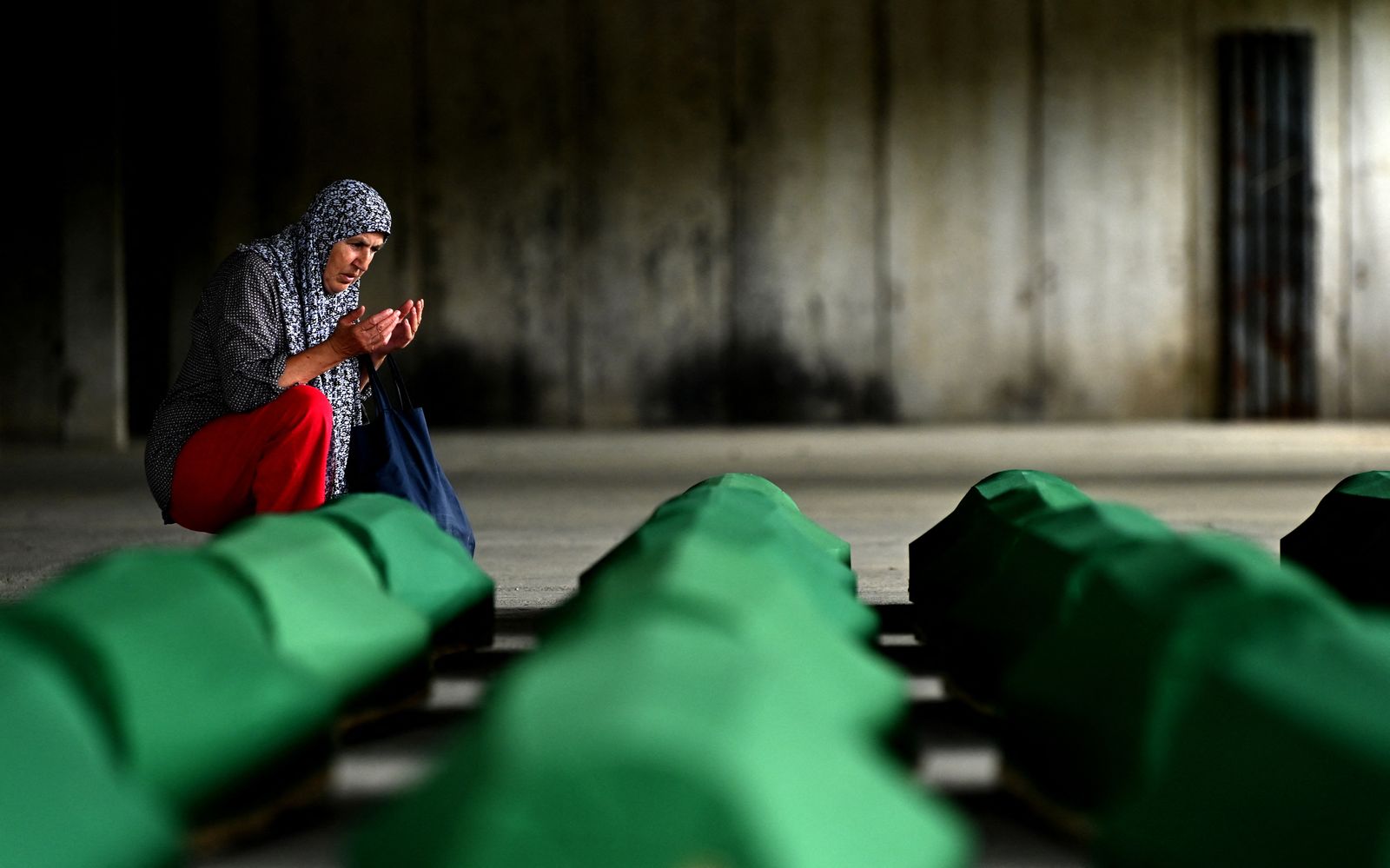 امرأة بوسنية نجت من مذبحة سريبرينيتشا تبكي بالقرب من الصناديق التي تحمل رفات أقاربها. 10 يوليو 2021 - AFP