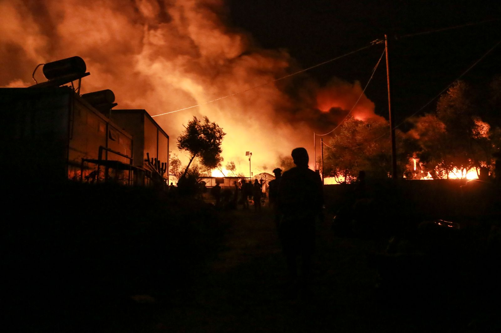 مهاجرون يغادرون مع اندلاع حريق في مخيم موريا في جزيرة ليسبوس اليونانية - AFP
