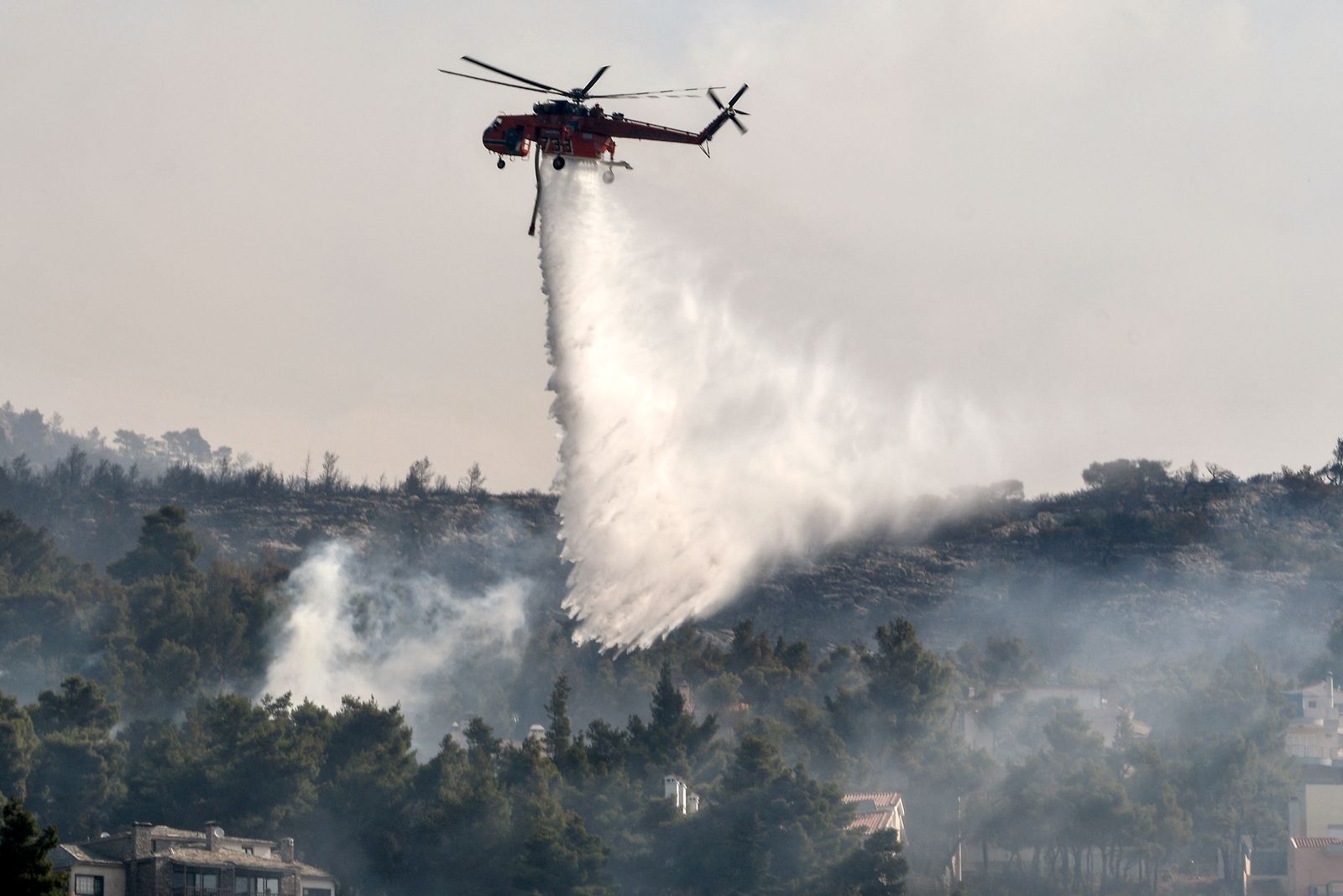طائرة هيلكوبتر تساعد على إطفاء حريق منطقة ثراكوماكدونيس شمال العاصمة الينانية أثينا، 7 أغسطس 2021 - AFP