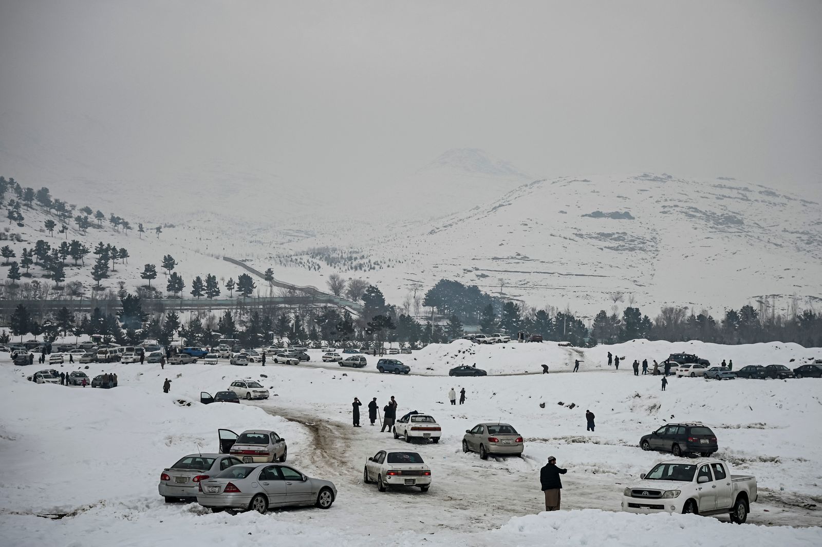 مواطنون أفغان يمشون على الجليد في إحدى ضواحي كابول - 7 يناير 2022 - AFP