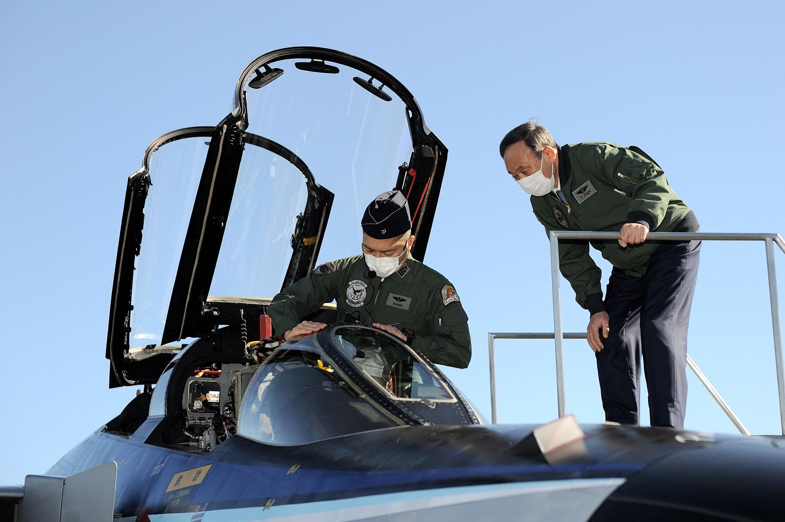 رئيس الوزراء الياباني السابق يوشيهيدي سوجا (يمين) ينظر داخل قمرة القيادة لطائرة مقاتلة من طراز (F4EJ Kai) تابعة لقوات الدفاع الذاتي الجوية اليابانية في قاعدة إيروما الجوية بمحافظة سايتاما، 28 نوفمبر 2020 - AFP