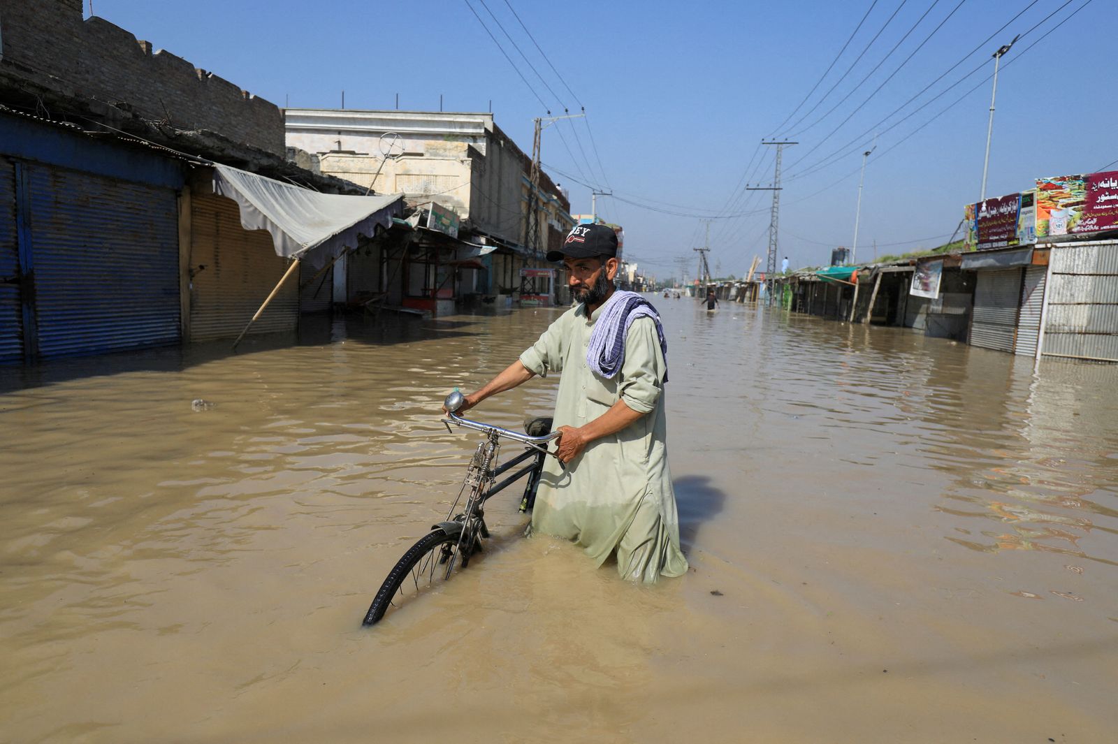 رجل يسير بدراجته في مياه الفيضانات بعد هطول الأمطار في ناوشيرا، باكستان 29 أغسطس 2022 - REUTERS