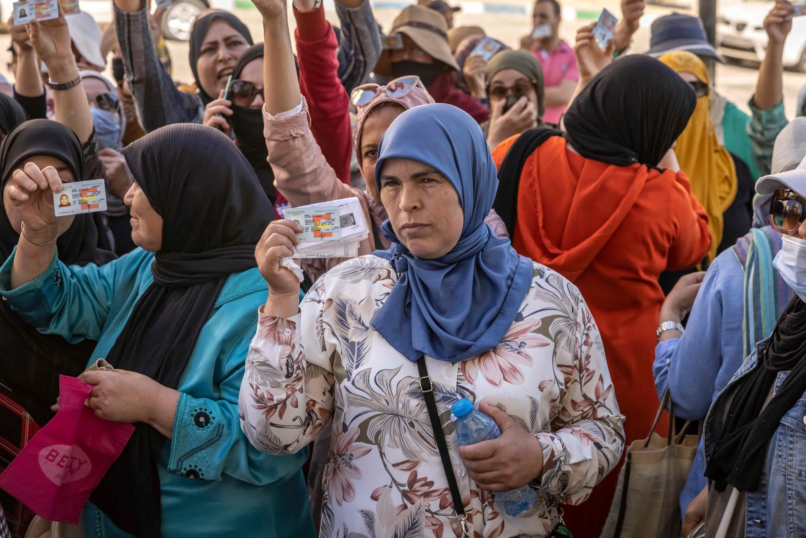 Moroccan workers gather with their work permits during a demonstration demanding the right to access the Spanish enclave of Ceuta without a visa, at Morocco's Fnideq border post on May 31, 2022. - Morocco and Spain have reopened the land borders between the north African country and the Spanish enclaves of Ceuta and Melilla, two years after they were shut due to Covid restrictions and a major diplomatic row. The reopening of the borders of the two enclaves initially remains limited to residents of Europe's open-borders Schengen area and their family members. (Photo by FADEL SENNA / AFP) - AFP