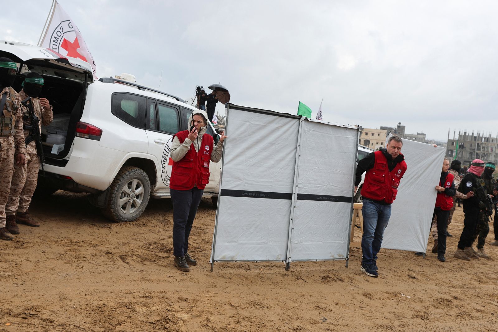 Members of the Red Cross stand near vehicles carrying coffins during the handover of deceased hostages Oded Lifschitz, Shiri Bibas and her two children Kfir and Ariel Bibas, seized during the deadly October 7, 2023 attack, to the Red Cross, as part of a ceasefire and hostages-prisoners swap deal between Hamas and Israel, in Khan Younis in the southern Gaza Strip, February 20, 2025. REUTERS/Ramadan Abed