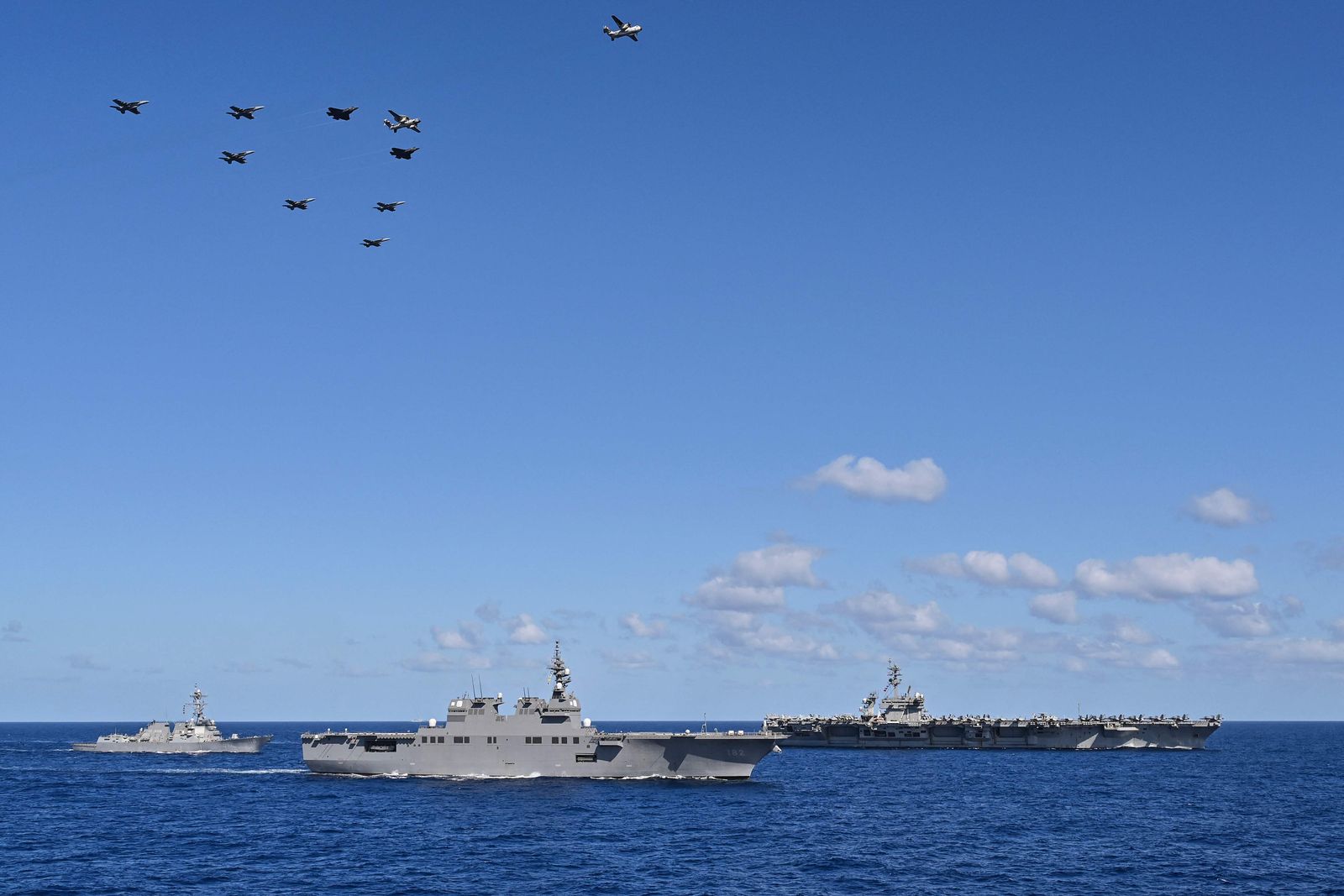 A formation of aircraft from the USS Carl Vinson aircraft carrier conducts a flyover past a flotilla, including the USS Theodore Roosevelt aircraft carrier (R), the Japan Maritime Self-Defense Force's Hyuga-class helicopter destroyer 'JS Ise' (C) and the Arleigh-Burke class guided missile destroyer USS Daniel Inouye (L) during a three-day maritime exercise between the US and Japan in the Philippine Sea, between Okinawa and Taiwan, on January 31, 2024. (Photo by Richard A. Brooks / AFP)