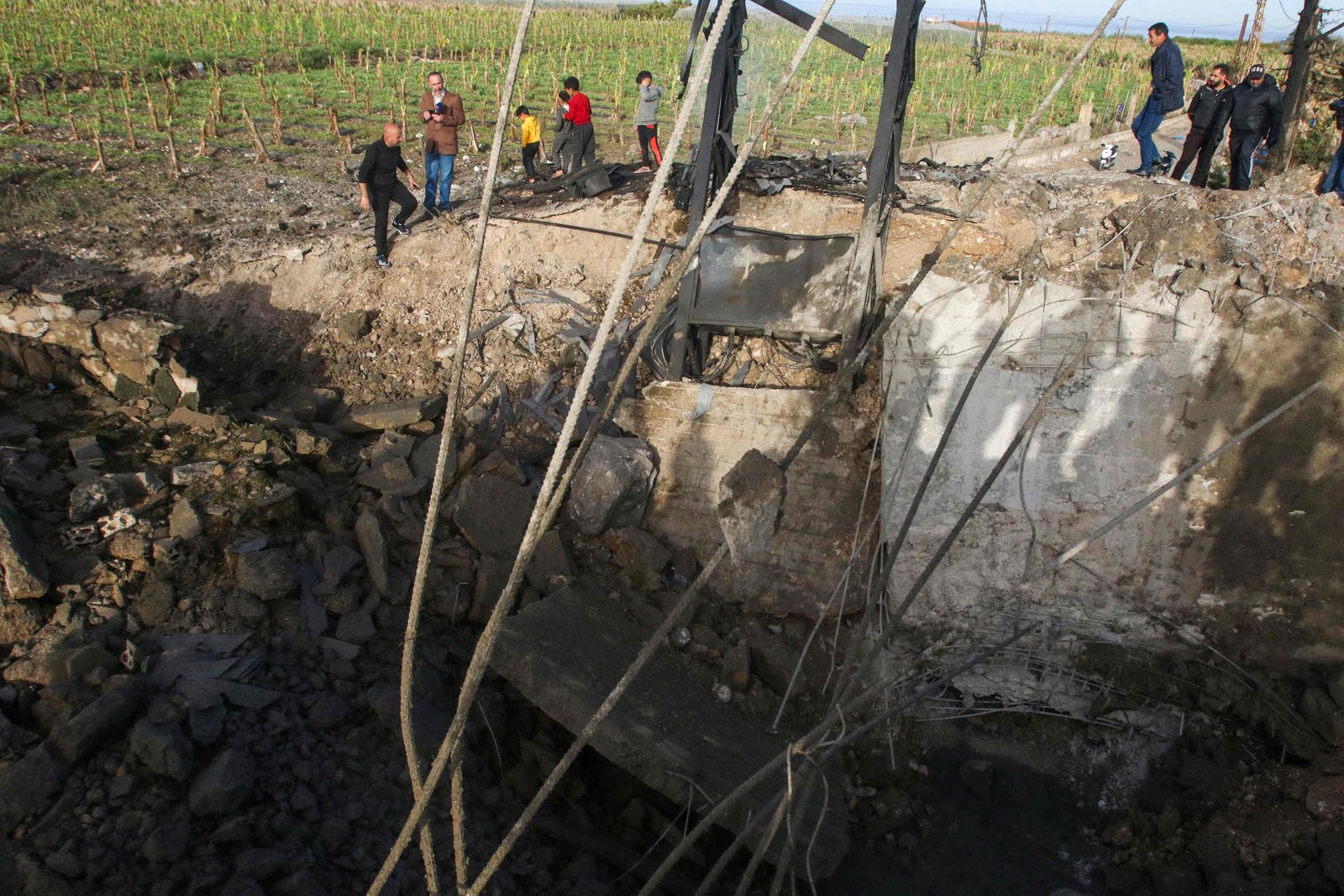 People check a damaged bridge following Israeli air strikes in Al Qulaylah, on the outskirts of Tyre, on April 7, 2023. - Israel launched air strikes before dawn on April 7 in the Gaza Strip and Lebanon, saying it was targeting Palestinian militant group Hamas in retaliation for several dozen rockets fired at Israel from both territories. (Photo by Mahmoud ZAYYAT / AFP) - AFP