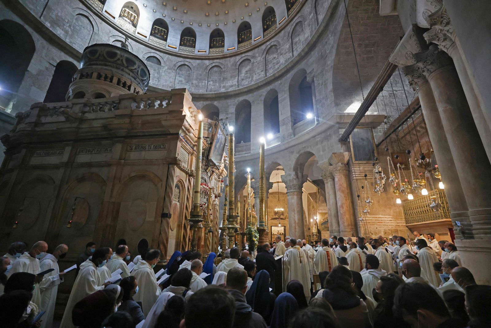 Christian worshippers pray during a mass to commemorate the Washing of the Feet around the Edicule, traditionally believed to be the burial site of Jesus Christ, on Holy Thursday at the Church of the Holy Sepulchre in Jerusalem, on April 1, 2021. - Holy Thursday or Maundy Thursday is the Christian holy day falling on the Thursday before Easter commemorating the Washing of the Feet and the Last Supper of Jesus Christ with the apostles. (Photo by Emmanuel DUNAND / AFP) - AFP