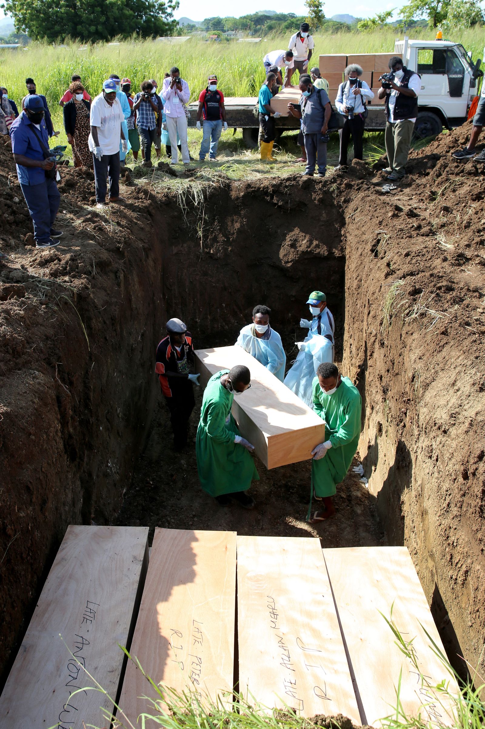Coffins are placed in a grave at 9 Mile Cemetery during a mass burial of at least 54 people who died from non-Covid-19 related issues and whose remains were unclaimed for at least six months in Port Moresby on December 8, 2021, as authorities hoped to alleviate space shortages at local morgues struggling with new Covid-19 related deaths. (Photo by Andrew KUTAN / AFP) / �The erroneous mention[s] appearing in the metadata of this photo by Andrew KUTAN has been modified in AFP systems in the following manner: [caption info: clarifying the deaths are non-Covid related] instead of [a Covid-19 buriel]. Please immediately remove the erroneous mention[s] from all your online services and delete it (them) from your servers. If you have been authorized by AFP to distribute it (them) to third parties, please ensure that the same actions are carried out by them. Failure to promptly comply with these instructions will entail liability on your part for any continued or post notification usage. Therefore we thank you very much for all your attention and prompt action. We are sorry for the inconvenience this notification may cause and remain at your disposal for any further information you may require.� - AFP