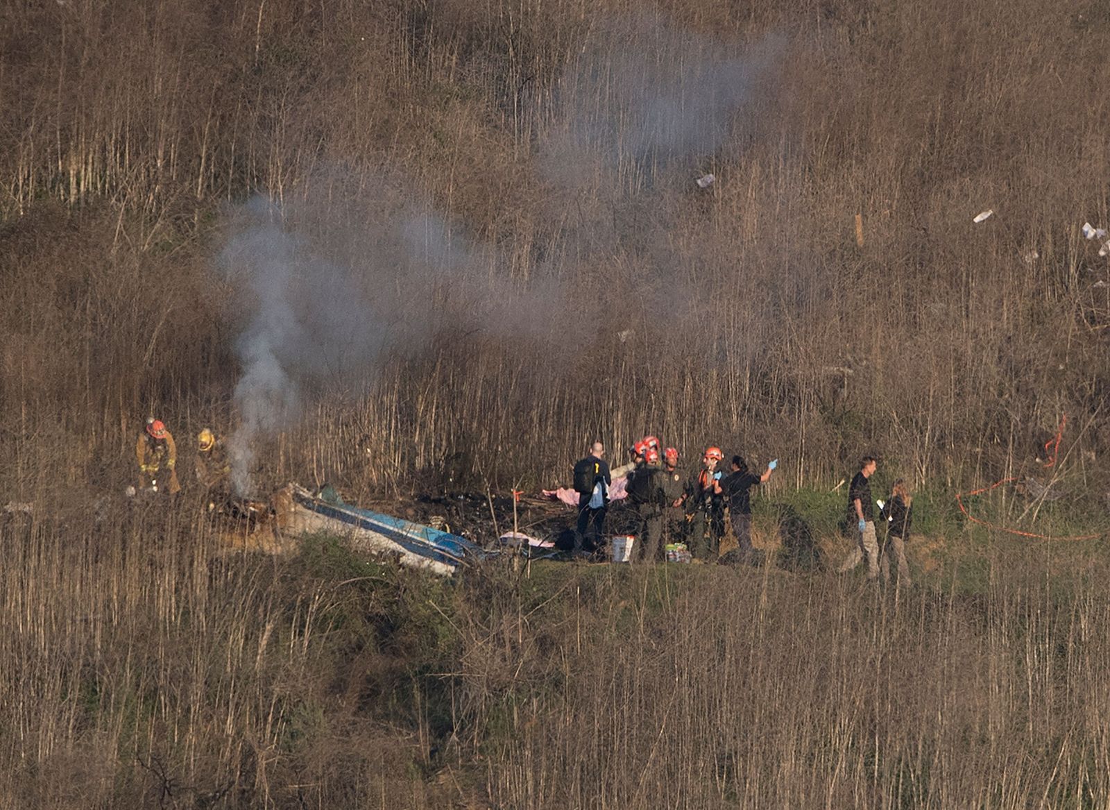 (FILES) In this file photo taken on January 26, 2020 Los Angeles County Fire Department firefighters and coroner staff check the wreckage at the scene of a helicopter crash in Calabasas. - A court case brought by Kobe Bryant's widow Vanessa Bryant over graphic photographs taken by first responders at the site of the helicopter crash that killed him was set to begin in the United States on August 10, 2022. (Photo by Mark RALSTON / AFP) - AFP