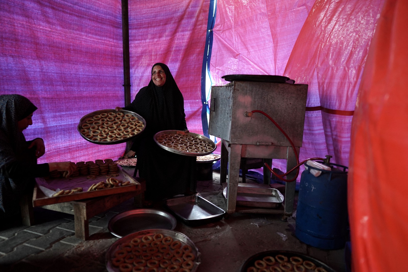 نساء فلسطينيات يعدن الكعك التقليدي احتفالاً بقدوم عيد الفطر داخل خيمة في دير البلح وسط قطاع غزة. 8 أبريل 2024