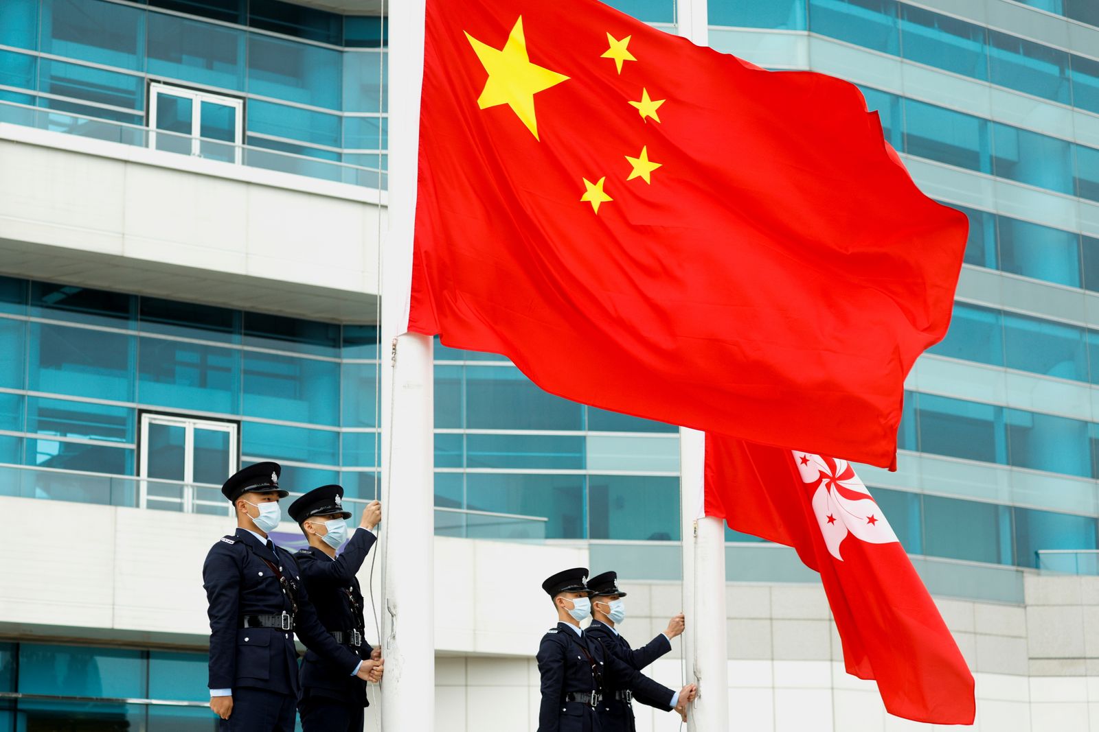 شرطيون يرفعون علمَي الصين وهونغ كونغ في الإقليم - 11 مارس 2021 - REUTERS