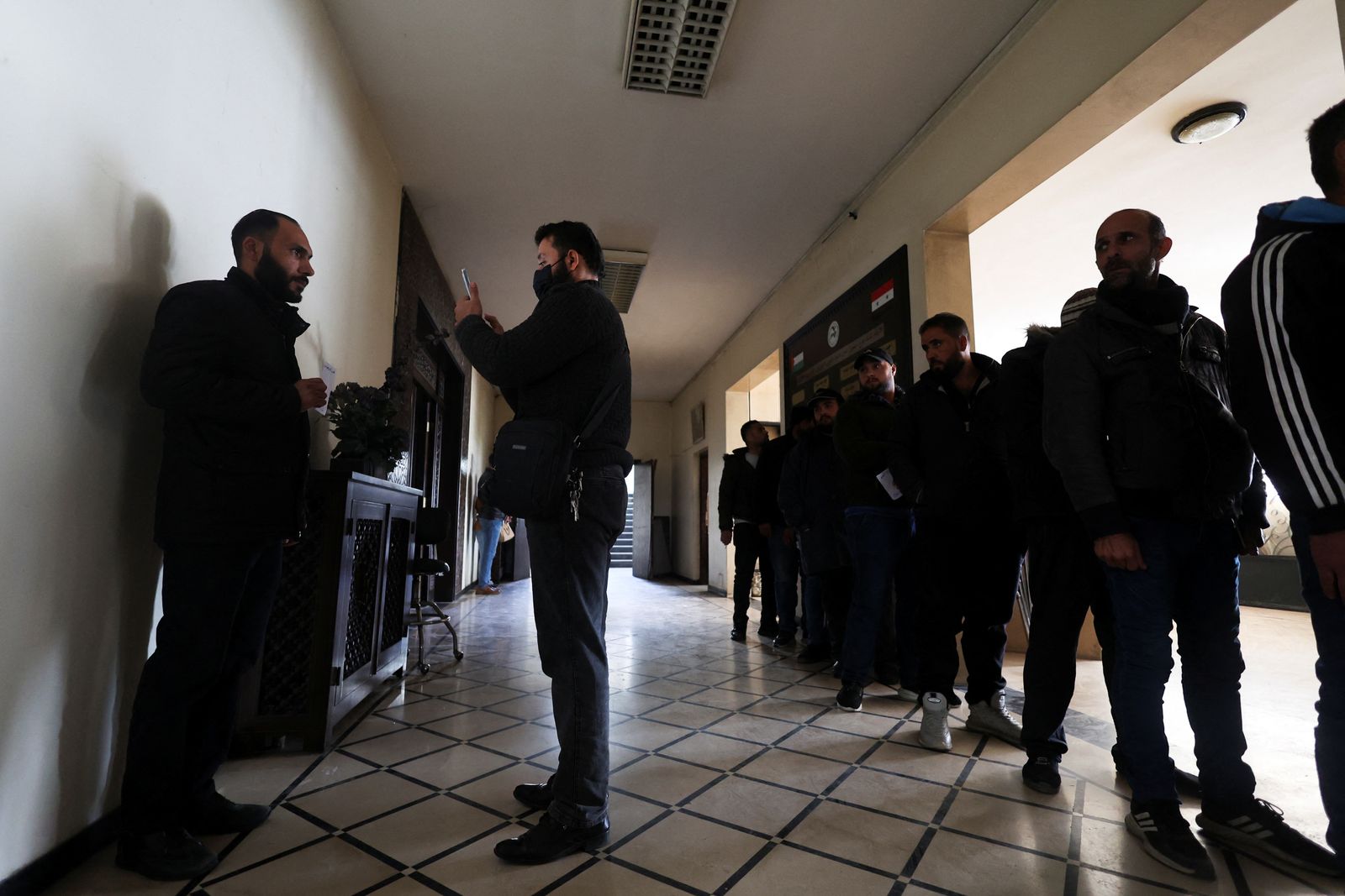 A former member of Syria's Bashar Al Assad's security forces is photographed, as others wait during the registration for the identification and reconciliation process, after Syria's Bashar al-Assad was ousted, in Damascus, Syria, December 21, 2024. REUTERS/Amr Abdallah