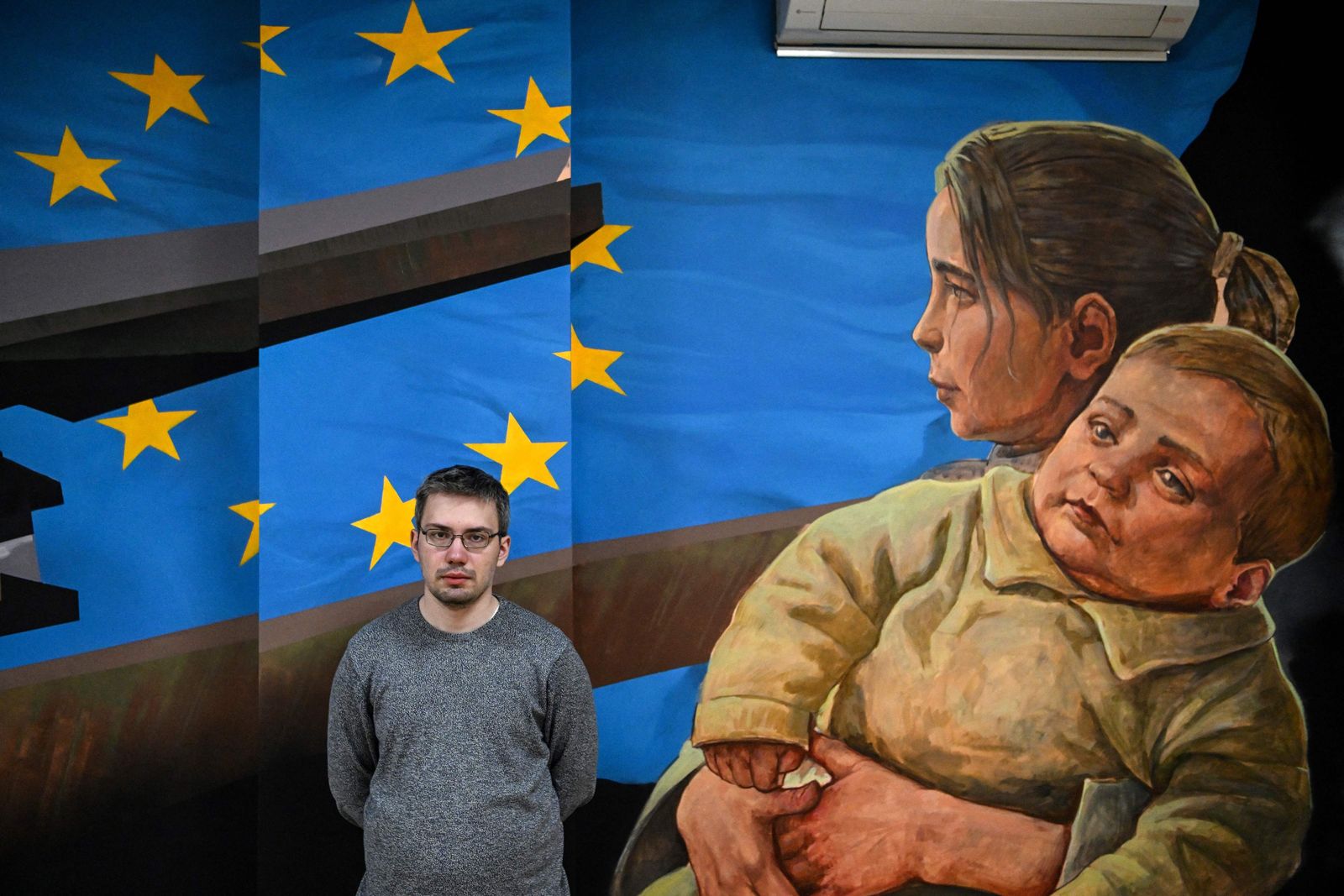 Museum's senior researcher Fyodor Kokin poses past a painting at the exhibition 