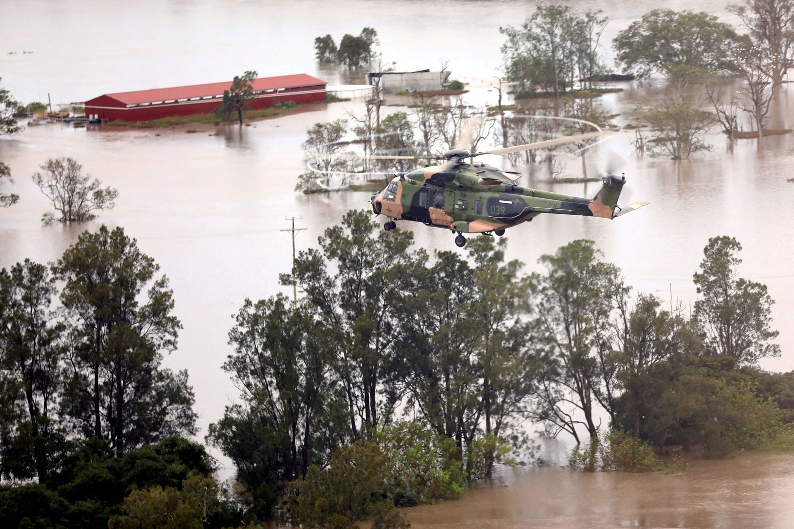 This handout photo taken on February 28, 2022 and received on March 1 from the Australian Defence Force (ADF) shows an Australian Army MRH-90 Taipan helicopter from the School of Army Aviation flying over flood-affected properties in the Ballina region of New South Wales. (Photo by Handout / Australian Defence Force / AFP) / ----EDITORS NOTE ----RESTRICTED TO EDITORIAL USE MANDATORY CREDIT 