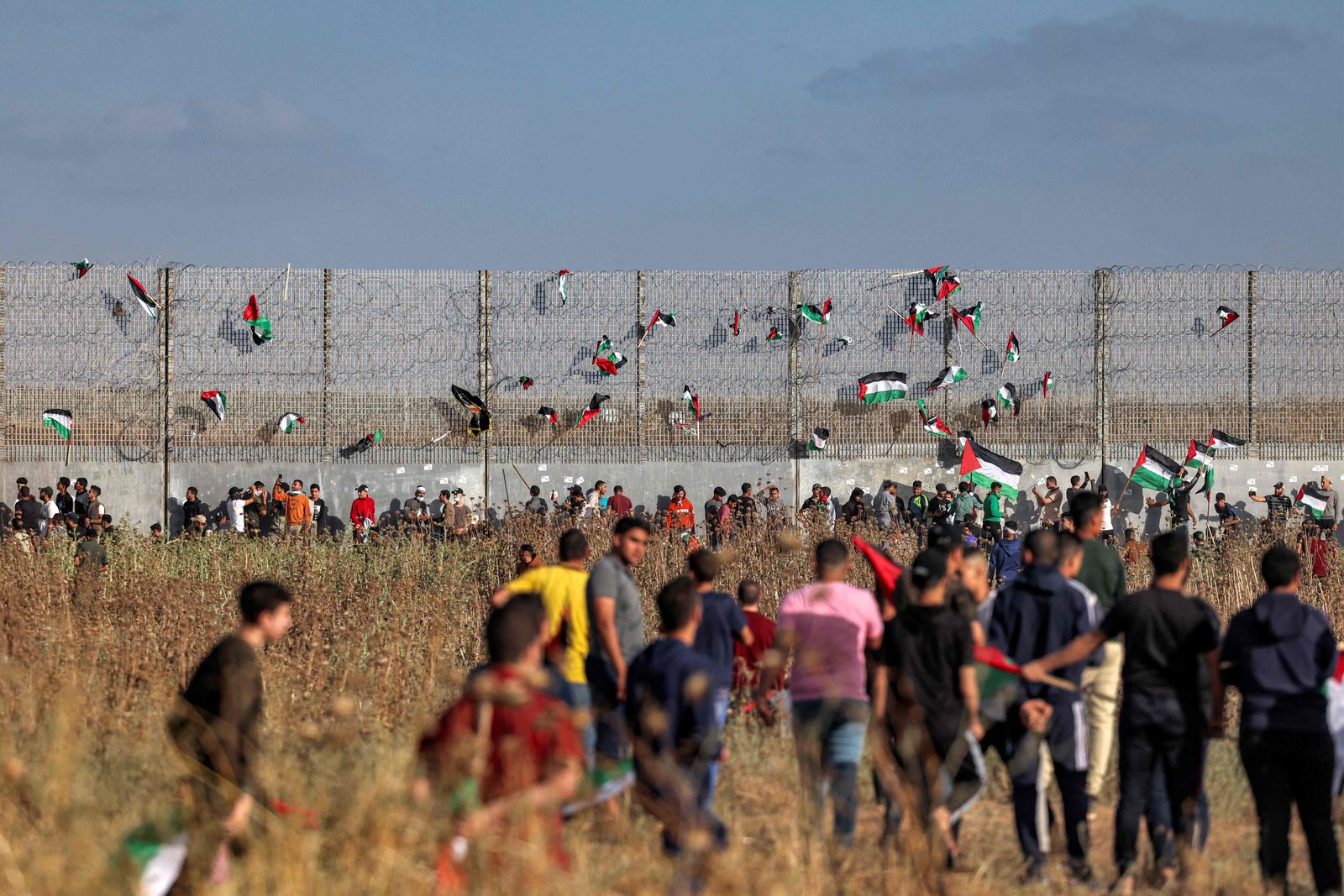 Palestinian flags are fixed to the barbed-wire fence during a 'flag march' demonstration along the border with Israel east of Gaza city on May 18, 2023 in response to the annual Israeli flag march marking 'Jerusalem Day' commemorating the old city's capture by Israel. (Photo by Mohammed ABED / AFP) - AFP