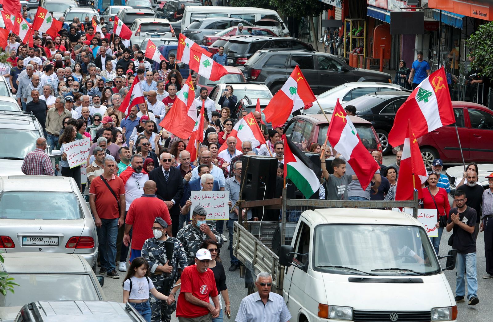 أشخاص يرفعون الأعلام واللافتات أثناء مسيرة خلال مظاهرة للاحتفال بعيد العمال في مدينة النبطية جنوبي لبنان. 1 مايو 2022 - REUTERS