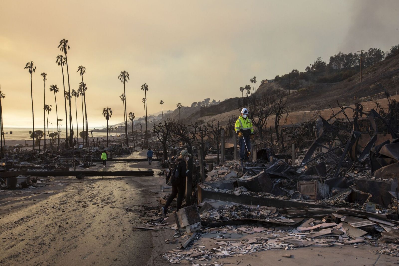 Residents look through their burned home for mementos at Pacific Palisades Bowl Mobile Estates during the Palisades fire in the Pacific Palisades area of Los Angeles, California, US, on Thursday, Jan. 9, 2025. The deadly fires in Los Angeles are forcing tens of thousands more residents from their homes as firefighters struggle to bring the blazes under control. Photographer: Jill Connelly/Bloomberg