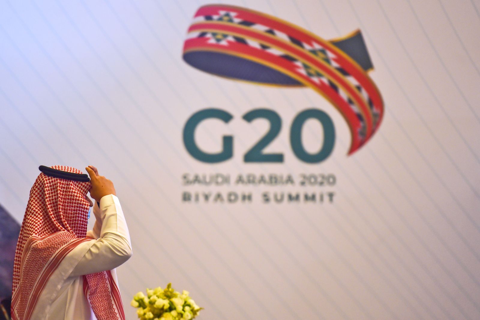 سعودي يمشي أمام شعار مجموعة العشرين قبل اجتماع لوزراء المالية ومحافظي البنوك المركزية في الرياض - 18 نوفمبر 2020 - AFP