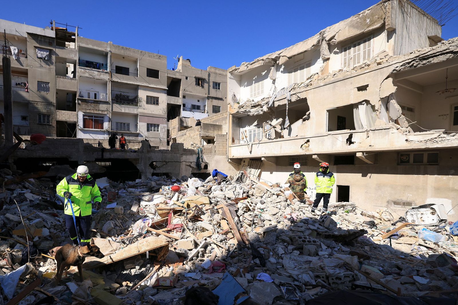 An Emirati rescuer, with the help of a dog, searches for victims amidst the rubble of a collapsed building in the regime-controlled town of Jableh in the province of Latakia, northwest of the Syrian capital, on February 10, 2023, in the aftermath of a deadly earthquake. - Aftershocks following the February 6 earthquake of 7.8-magnitude in Turkey and Syria, have added to the death toll and further upended the lives of survivors. (Photo by Karim SAHIB / AFP) - AFP