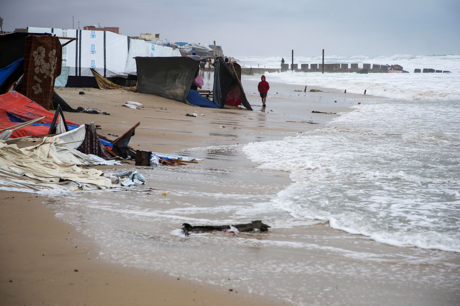 A displaced Palestinian boy walks near flooded tents following rising sea levels and heavy rainfall, amid the ongoing conflict between Israel and Hamas, in Khan Younis in the southern Gaza Strip, November 25, 2024. REUTERS/Hatem Khaled