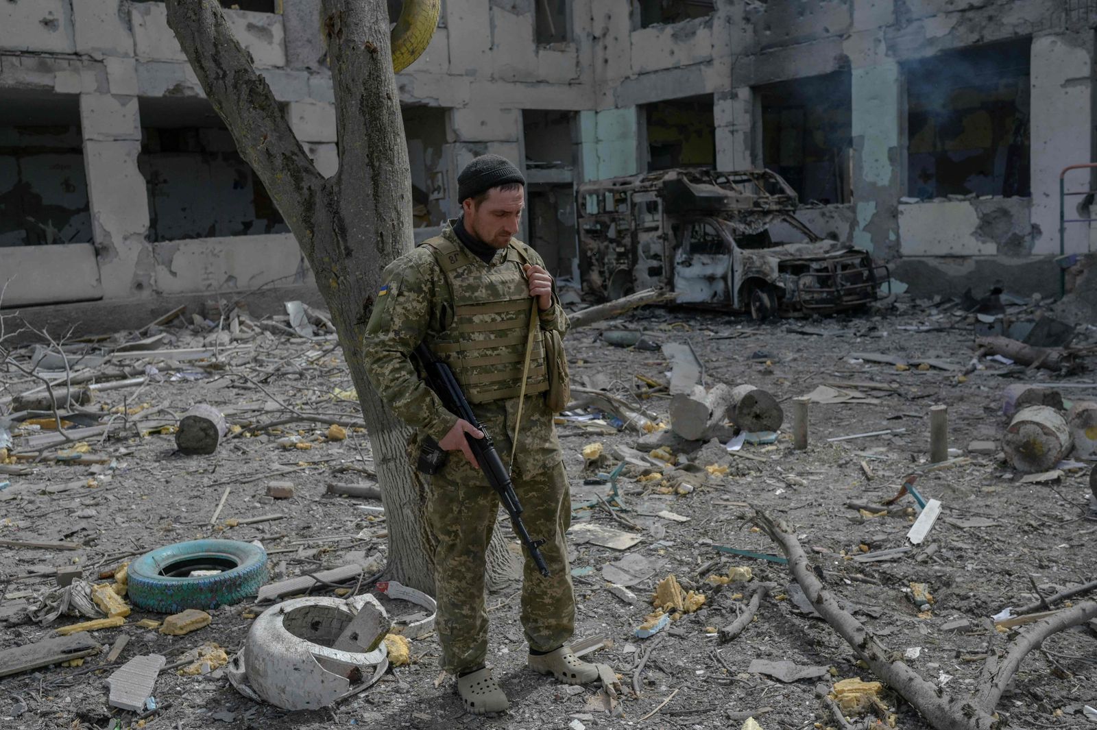 جندي أوكراني يقف خارج مدرسة مدمّرة بصواريخ روسية في قرية قرب مدينة خيرسون الأوكرانية -1 أبريل 2022 - AFP