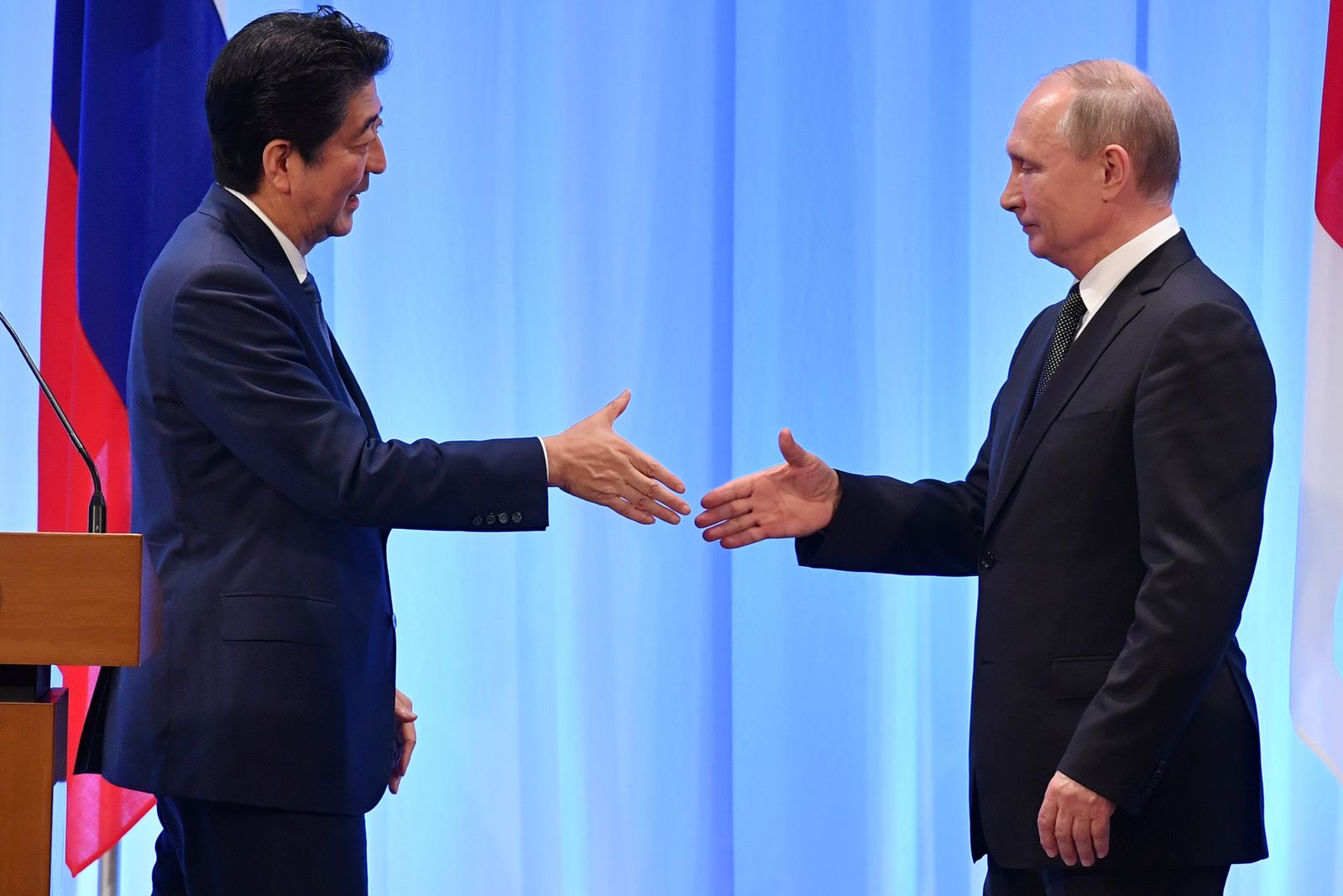 الرئيس الروسي فلاديمير بوتين ورئيس الوزراء الياباني السابق شينزو آبي يتصافحان بعد قمة لمجموعة العشرين في أوساكا - 29 يونيو 2019 - REUTERS