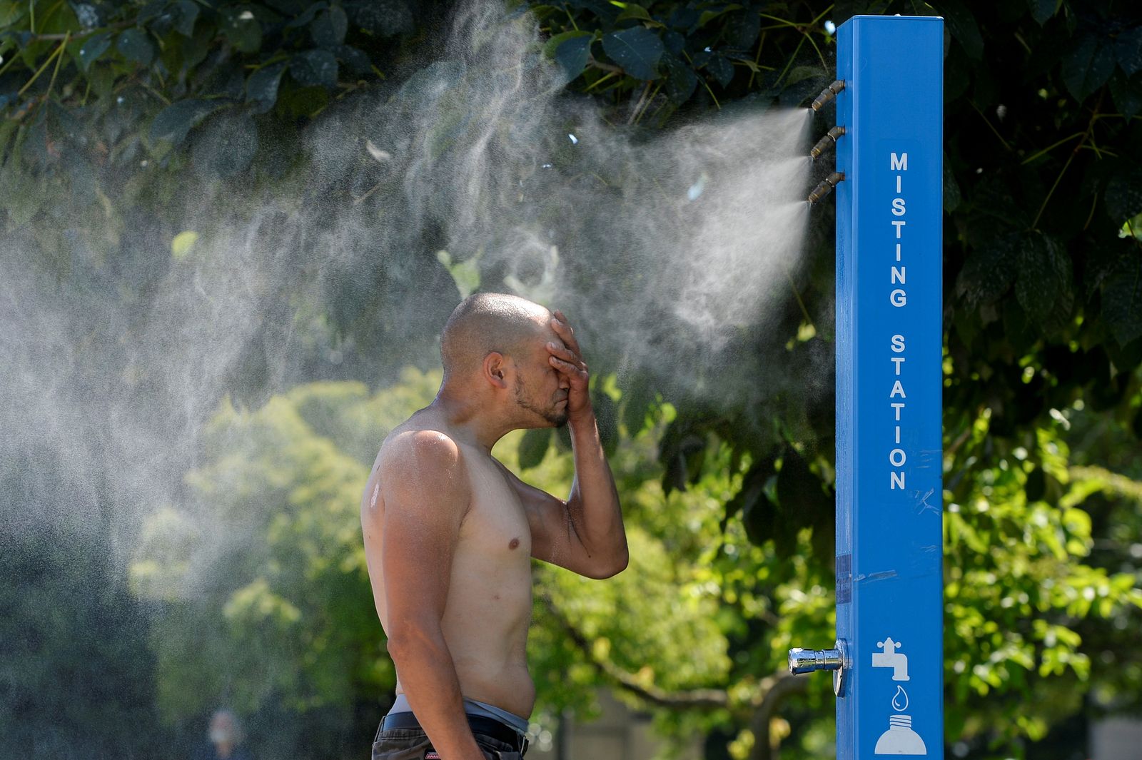 رجل عند منطقة ترش رذاذ ماء في فانكوفر كندا . - REUTERS