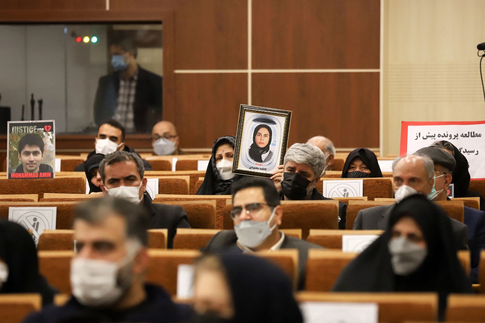 عائلات تحمل صور عدد من ضحايا الطائرة الأوكرانية خلال إحدى جلسات المحاكمة في طهران - 21 نوفمبر 2021 - AFP