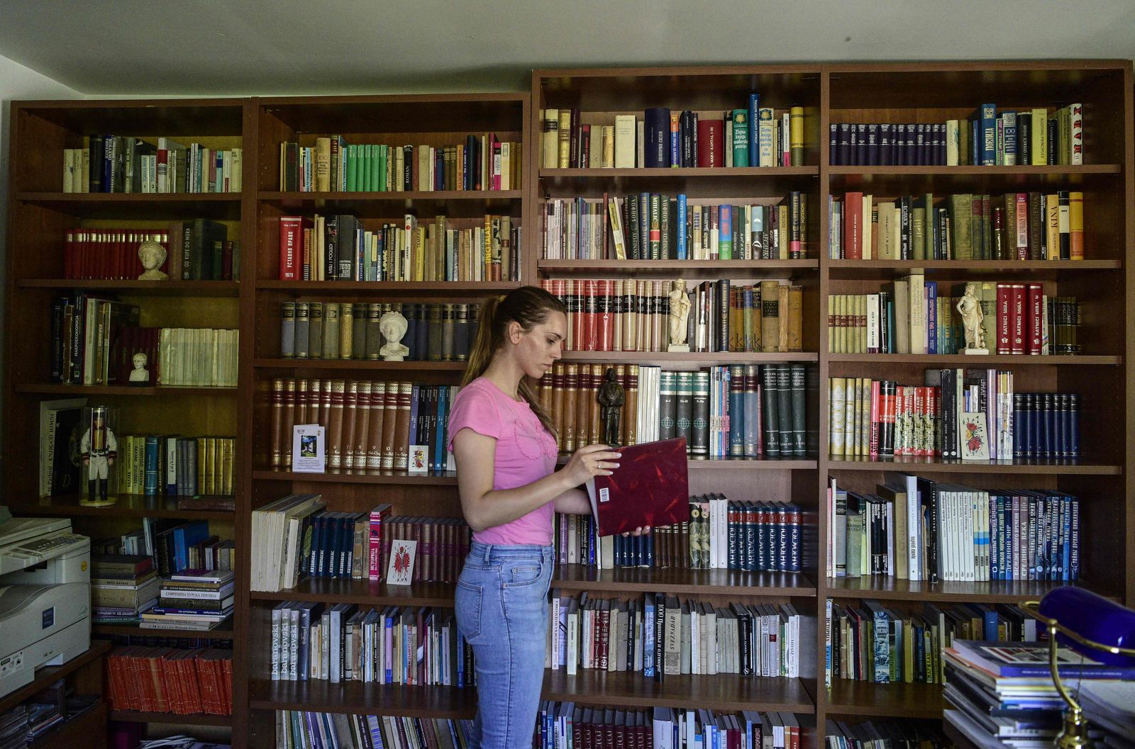 In this photograph taken on July 11, 2022, a visitor looks through a volume in the library of Stevo Stepanovski in the village of Babino in western Macedonia - Most people packed up and left the remote North Macedonia village of Babino years ago. But Stevo Stepanovski and his remarkable collection of 20,000 books passed down in his family from generation to generation stayed put in his almost abandoned valley. The library began with Stepanovski's great-grandfather who was given his first tranche of books by passing Ottoman soldiers in the late 19th century. (Photo by Robert ATANASOVSKI / AFP) - AFP