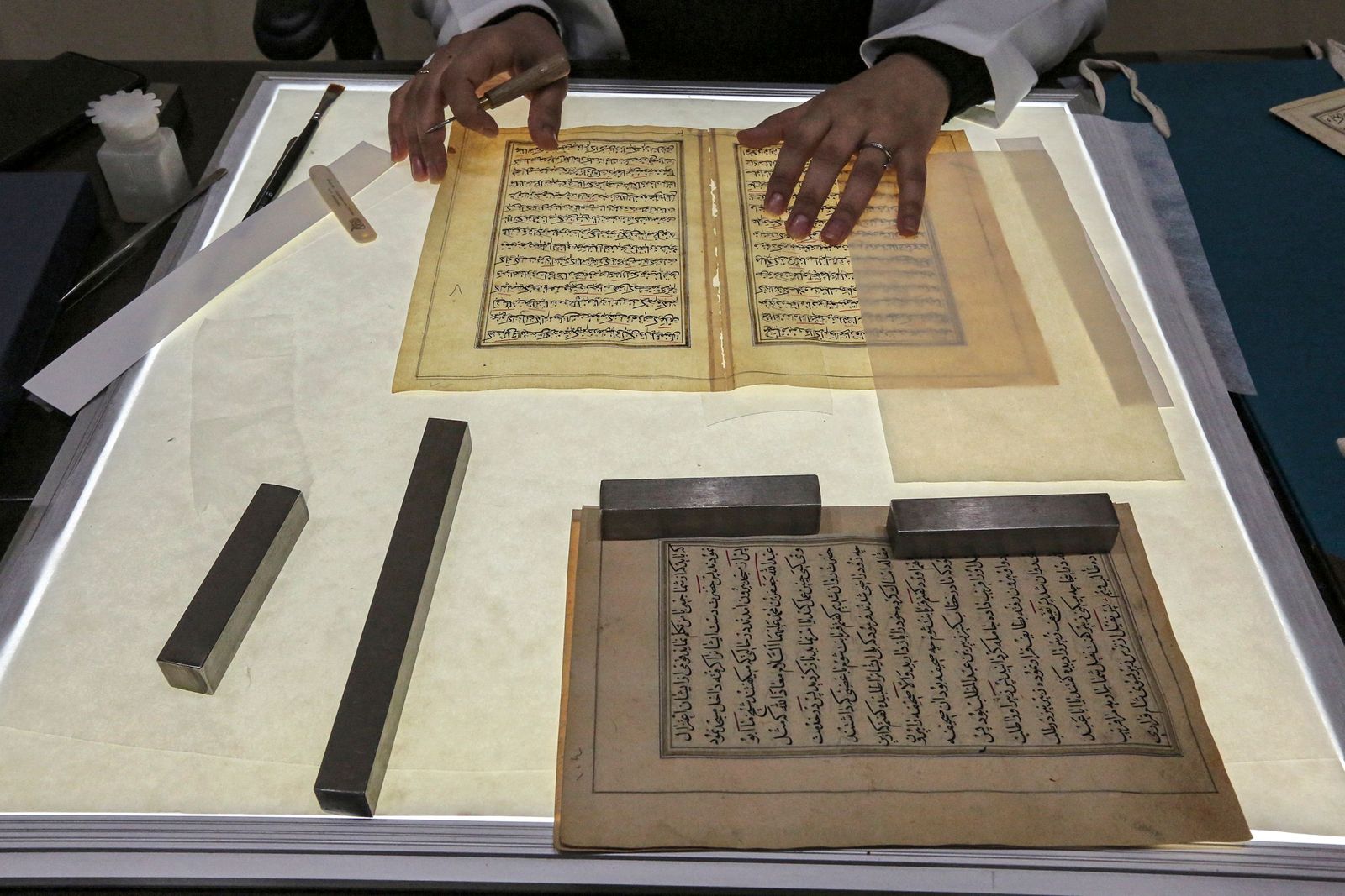 A conservator pieces together a Turkish-language manuscript undergoing restoration at the Iraqi Manuscript House's resoration lab in Iraq's capital Baghdad on December 6, 2022. - A curator in Baghdad pores over a 17th-century Persian manuscript, inside an annex of Iraq's national museum where she patiently undertakes delicate restoration work on the religious text. It is part of an enormous challenge Iraq has set itself -- preserving and digitising 47,000 of its ancient manuscripts and books. (Photo by Sabah ARAR / AFP) - AFP