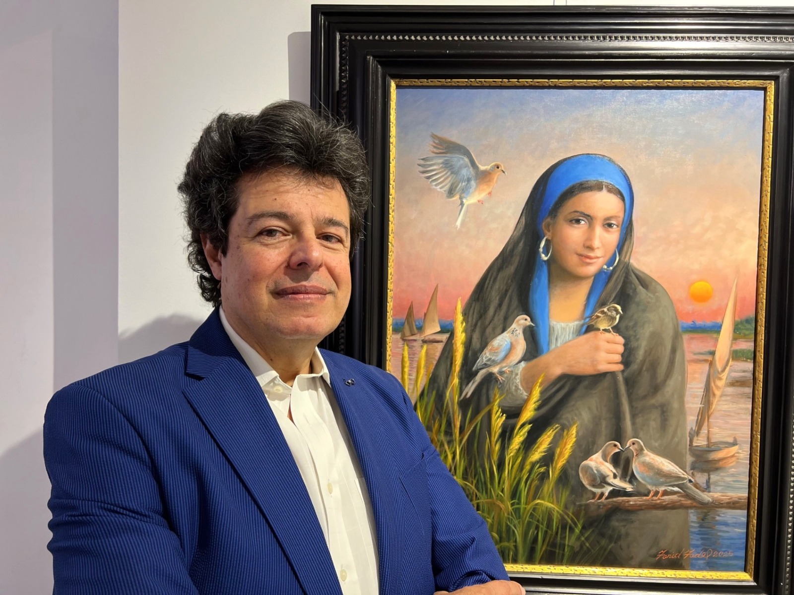 الفنان فريد فاضل إلى جانب لوحاته