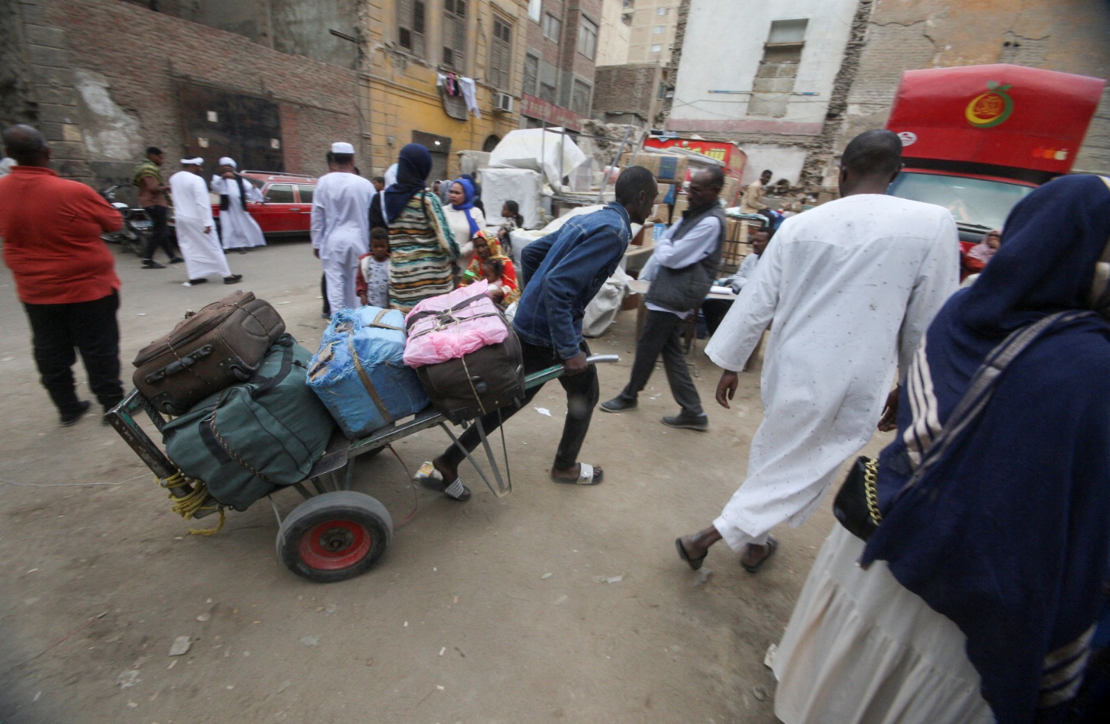 لاجئون سودانيون ينتظرون بجوار أمتعتهم في نقطة تجمع للحافلات بالقاهرة في طريق عودتهم الطوعية من مصر إلى السودان. 11 أبريل 2025