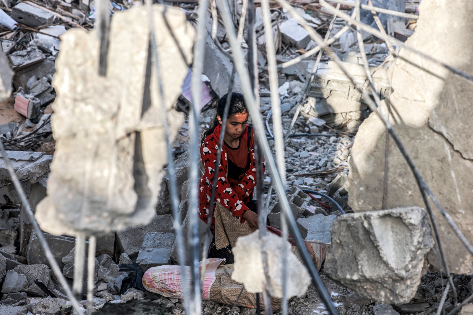 فتاة فلسطينية تبحث عن أغراضها بين ركام منزلها المُدمر جرّاء الغارات الإسرائيلية على رفح جنوب قطاع غزة. 24 أبريل 2024