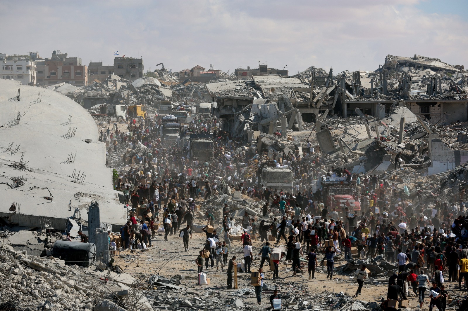 فلسطينيون يجمعون إمدادات المساعدات من الشاحنات التي دخلت غزة وسط وقف إطلاق النار بين إسرائيل وحركة حماس في خان يونس بجنوب قطاع غزة. 12 أكتوبر 2025
